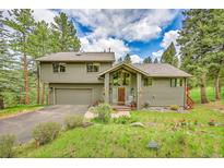 Charming two-story home with a 2-car garage, complemented by a welcoming front porch and lush landscaping at 28065 Camel Heights Cir, Evergreen, CO 80439