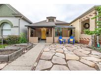 Charming bungalow with a bright yellow door, stone patio, and lovely landscaping at 30 Fox St, Denver, CO 80223
