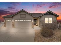 Charming ranch-style home with stone accents, a three-car garage, and a landscaped front yard at sunset at 10882 E 162Nd Pl, Brighton, CO 80602