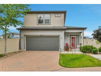 Charming two-story home features a gray exterior, two-car garage and a red front door at 5131 Andes St, Denver, CO 80249