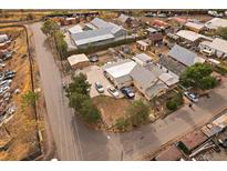 An aerial view of a yellow home with a detached garage and other assorted buildings and parked cars nearby at 5182 Thompson Ct, Denver, CO 80216