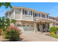 Charming two-story home featuring a brick facade, well-maintained lawn, and attached two-car garage at 15353 E 98Th Pl, Commerce City, CO 80022