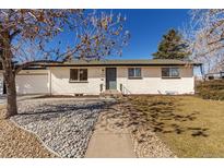 Charming ranch-style home with a white brick exterior, a well-manicured lawn, and a walkway to the front door at 6699 S Pennsylvania St, Centennial, CO 80121