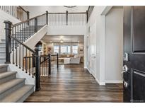 Grand foyer featuring a staircase with iron railings, dark wood floors, and an open view to the living room at 6679 Kenzie Cir, Castle Pines, CO 80108