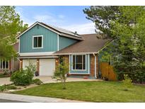 Charming two-story home with blue siding, brick accents, attached two-car garage, and well-manicured front lawn at 8140 S Storm King Peak, Littleton, CO 80127