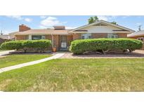 Charming brick home featuring a well-maintained lawn and mature landscaping at 4705 Upham St, Wheat Ridge, CO 80033