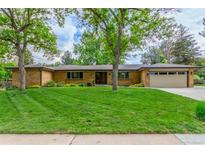 Charming brick home featuring a lush green lawn, mature trees, and a spacious two-car garage at 5890 W Quarles Dr, Littleton, CO 80128