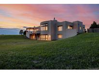 Stunning home exterior against a colorful sunset sky, highlighting the unique architectural design and lush greenery at 1764 Mesa Ridge Ln, Castle Rock, CO 80108