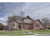 Charming two-story brick home featuring a manicured lawn, bay windows, and a beautifully tiled roof at 15857 E Aberdeen Ave, Centennial, CO 80016