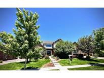 Charming two-story home featuring a lush front yard, mature trees, and manicured landscaping at 15857 E Aberdeen Ave, Centennial, CO 80016
