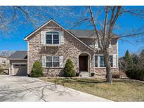 Charming stone-and-siding two-story home with well-manicured front lawn at 12518 W 77Th Pl, Arvada, CO 80005