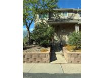 Inviting townhome with a brick facade, complemented by lush landscaping and a stone retaining wall, leading to a welcoming front entrance at 1470 S Quebec Way # 8, Denver, CO 80231