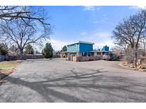 Bright blue two-story home featuring a spacious parking area and unique architectural details at 7400 W Quincy Ave, Littleton, CO 80123