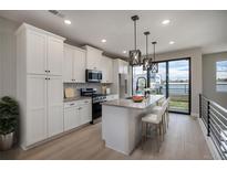 Modern white kitchen featuring an island with counter seating, stainless steel appliances, and hardwood flooring at 2078 S Holly St # 2, Denver, CO 80222