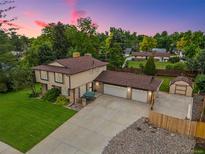 Two-story home boasts a spacious driveway, charming shed, lush lawn, and an attached two-car garage at 5954 W Leawood Dr, Littleton, CO 80123