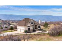 Stately stucco home featuring grand architecture and breathtaking mountain views, set amidst a serene landscape at 3074 Castle Butte Dr, Castle Rock, CO 80109