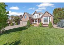 Beautiful two-story brick home with a well-manicured lawn and attached two car garage at 6987 Esperanza Dr, Castle Pines, CO 80108