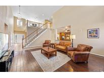 Open-concept living room featuring hardwood floors, staircase, and abundant natural light at 6987 Esperanza Dr, Castle Pines, CO 80108