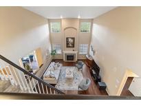 Bright living room featuring soaring ceilings, a fireplace, and large windows that flood the space with natural light at 6987 Esperanza Dr, Castle Pines, CO 80108