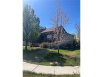 Charming two-story home with landscaped front yard and mature trees offering shade and curb appeal at 2170 Granite Dr, Brighton, CO 80603
