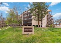 Morningside Condominiums exterior view shows building behind stone sign on green lawn at 3470 S Poplar St # 102, Denver, CO 80224