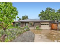 Charming brick home featuring solar panels, a well-kept yard, and an attached one-car garage at 6051 Ivanhoe St, Commerce City, CO 80022
