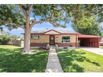 Charming brick home featuring mature trees, a well-manicured lawn, and a convenient carport at 7172 Kalamath St, Denver, CO 80221