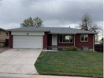 Charming brick home featuring an attached garage, well-manicured lawn, and a welcoming front entrance at 1152 S Eaton St, Lakewood, CO 80232