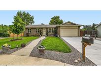 Charming brick home with a well-manicured front yard, landscaped garden beds, and a two-car garage at 11707 W 65Th Cir, Arvada, CO 80004