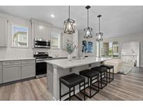 Stylish kitchen featuring gray cabinetry, stainless steel appliances, and a large island with modern pendant lighting at 16421 Askins Loop, Parker, CO 80134