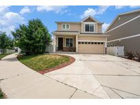 Two-story tan home featuring a two-car garage, manicured lawn, and inviting front entrance at 5572 Killarney St, Denver, CO 80249
