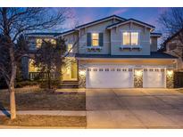 Inviting two-story home featuring a stone-accented three-car garage and a beautifully landscaped front yard at twilight at 683 Ridgemont Cir, Highlands Ranch, CO 80126