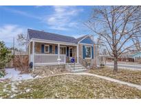 Charming home featuring a welcoming front porch, blue shutters, mature trees, and well-maintained landscaping at 1185 Xanthia St, Denver, CO 80220