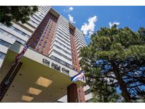 High-rise condominium building featuring brick and white facade under a sunny sky and mature trees at 3131 E Alameda Ave # 1604, Denver, CO 80209