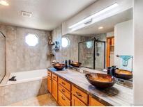 Bright bathroom featuring dual sinks, a glass enclosed shower, and a soaking tub beneath unique octagonal windows at 1678 S Parkdale Cir, Erie, CO 80516