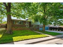 Charming two-story home with brick and light blue siding, mature trees, and a well-manicured lawn at 1905 S Linden Ct, Denver, CO 80224