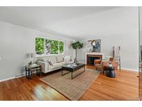 Bright living room with hardwood floors, area rug, and brick fireplace at 1905 S Linden Ct, Denver, CO 80224