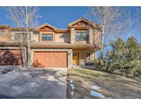 Charming two-story home with stone accents, a two-car garage, and a welcoming yellow front door at 995 Nob Hill Rd, Evergreen, CO 80439
