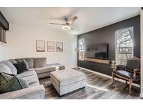 Spacious living room featuring L-shaped sofa, wood-look floors, and a modern TV setup at 8685 Carr Loop, Arvada, CO 80005