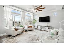 Bright living room with a ceiling fan, large windows, and modern furniture at 18143 E 104Th Way, Commerce City, CO 80022
