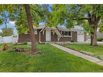 Charming brick home featuring a well-manicured lawn and inviting walkway to the front door at 8137 Vanguard Dr, Denver, CO 80221