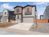 Charming two-story home with neutral siding, stone accents, and a two-car garage at 13531 E 99Th Pl, Commerce City, CO 80022