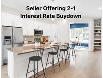 Modern kitchen boasts white cabinets, stainless steel appliances, and a stylish island with bar seating and sink at 4730 S Acoma St, Englewood, CO 80110