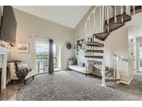 Bright living room featuring a spiral staircase, balcony access with mountain views, and neutral decor at 10872 W Evans Ave # 3D, Lakewood, CO 80227
