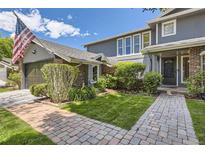 Charming two-story home featuring a brick pathway, manicured lawn, and an American flag waving proudly at 6338 S Oneida Ct, Centennial, CO 80111