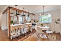 Modern kitchen features an island with bar seating and an adjacent dining area with natural light at 2598 Teller St, Lakewood, CO 80214