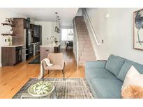 Open-concept living room features hardwood floors, modern furnishings, and a staircase leading to the upper level at 1581 Wolff St, Denver, CO 80204