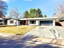 Beautifully renovated ranch home with white painted brick, modern black garage door, and well-manicured lawn at 1559 S Forest St, Denver, CO 80222