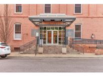 Building entrance with a glass entryway and stairs, set in a brick building with sidewalk and parking at 1143 Auraria Pkwy # 101, Denver, CO 80204
