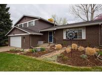Charming home featuring a brick facade, well-manicured garden, and attached garage for convenient parking at 8229 Estes Ct, Arvada, CO 80005
